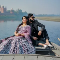 Another perspective from the Yamuna, this shot captures the couple in their ornate outfits, looking like royalty as they float by the Taj Mahal.