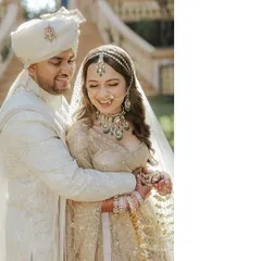 A candid moment of joy between the happy couple. The bride's stunning green-beaded jewelry adds a subtle pop of color to her intricate ivory chikankari lehenga, showcasing how small details can elevate a look.
