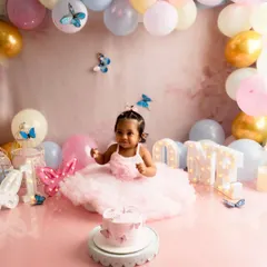 A wider view of a complete cake smash setup. This butterfly theme includes a custom backdrop, a balloon arch in pastel colors, and light up letters spelling 'ONE' to create a dreamy, celebratory atmosphere.