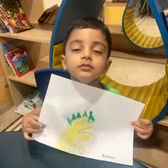A proud student shows off his drawing of a dinosaur, created during a science camp activity. Art is a great way for children to express what they've learned.