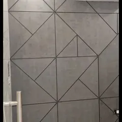 A concrete-textured wall with a geometric pattern created by dark grout lines, blending industrial texture with sharp, modern design.