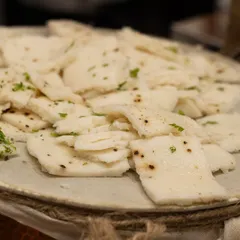 A close-up of our perfectly steamed white dhokla, garnished with fresh cilantro. This traditional dish is a comforting and beloved addition to any vegetarian menu.