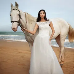 A full-length view of the model and horse on the beach. The natural, golden hour light creates a soft, romantic mood, perfect for a pre-wedding or conceptual fashion shoot.