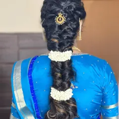 A modern take on the traditional braid, this fishtail braid is accented with jasmine flowers and a sun-themed hair accessory.