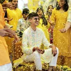 The Haldi ceremony is all about unrestrained happiness. Capturing the groom amidst a shower of flower petals, with a huge smile on his face, perfectly freezes that peak moment of celebration with friends and family.