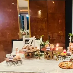 A beautifully arranged buffet table for a Diwali cards party. The setup features a mix of rustic and elegant serving dishes, candles, and floral arrangements to create a warm and inviting ambiance.