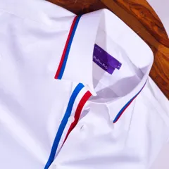 A crisp white shirt with a twist. This piece features a bold red and blue striped lining on the collar and placket for a pop of color.