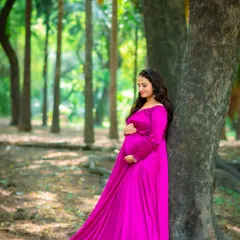 The vibrant magenta of this gown stands out beautifully in the woods. This is a wonderful example of a solo maternity portrait that is both serene and striking.