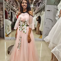A smile that says it all! This client is glowing in her custom pink gown, featuring a cascade of white and green floral appliqués that we designed just for her.