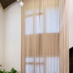 We installed floor-to-ceiling sheer curtains in this double-height room to manage the abundant natural light. This feature adds a touch of softness and drama while emphasizing the impressive scale of the windows and the height of the space.