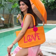A cheerful poolside shot of a model in a pink bikini and sarong, holding a large orange "LOVE" tote bag and umbrella. This image captures a fun, vibrant vacation mood perfect for a resort wear brand.