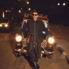 A wide shot of Ranveer with the iconic kaali-peeli taxi. The styling was designed to be both high-fashion and grounded in a cool, urban Mumbai context.