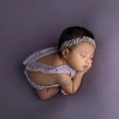 A beautiful top down view of the 'taco' pose, showing how the baby is curled up comfortably. The purple lace romper adds a lovely textural detail.
