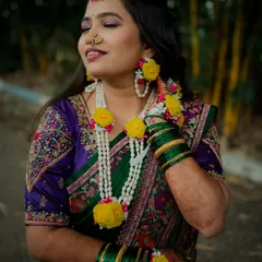 The Haldi glow is real. This bride, with her eyes closed in a moment of bliss, looks absolutely serene, adorned with fresh flower jewelry that complements her green and purple saree.