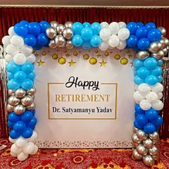 A formal retirement party balloon arch in blue, white, and silver, framing a personalized backdrop for the retiree.