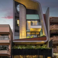 A view of the Luminara residence at dusk, where the sculptural form is highlighted by carefully integrated lighting. The curved roofline and layered volumes create a sense of movement, showcasing a design that is both an architectural statement and a comfortable home.