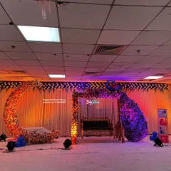 This wide shot shows the full scale of the baby shower stage decoration. You can see the floral arch over the swing, the large peacock feather-inspired floral arrangement, and the crescent moon cradle, all set up on a raised platform for maximum visibility.