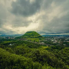 The dramatic landscape of Nashik during the monsoon, with a lush green hill under a stormy sky. The dynamic range on modern phones is incredible for capturing scenes like this.