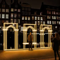 The human scale of the installation is an essential part of its design. Here, a visitor stands within the primary archway, demonstrating how the piece serves as both a large scale urban landmark and an intimate, interactive photo opportunity.