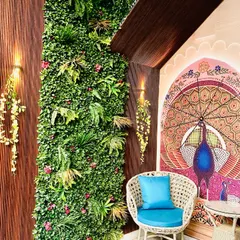 We completely revamped this entrance with a lush green wall, a traditional peacock mural, and comfortable seating to create a welcoming and serene nook.