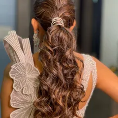 The back view of this textured ponytail, highlighting the voluminous curls and the sparkling diamond cuff that holds it all together.