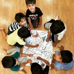 Collaboration in our creative corner. A group of boys works together on a giant coloring sheet, a simple activity that encourages sharing, communication, and collective artistic expression.