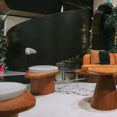 A stylish waiting area featuring custom curved wooden tables and comfortable seating. This design moves away from traditional lobby furniture to create a more relaxed and sophisticated lounge-like experience for visitors.