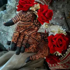 A close-up of the developed henna stain, showing the crisp lines and dark color against the bride's red and white floral jewelry.