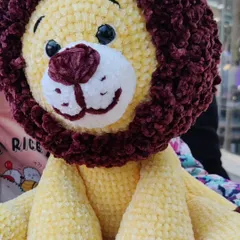A close-up on the friendly, hand-stitched face of my custom lion plushie.