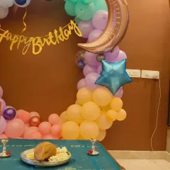 A whimsical moon and stars themed decoration for a fourth birthday. The pastel balloon ring is accented with a crescent moon and star foil balloons for a magical touch.