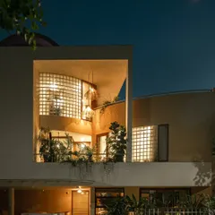A wider perspective of the home at dusk. The illuminated balcony garden and lower-level planting work together to create a cohesive landscape design that envelops the entire structure.