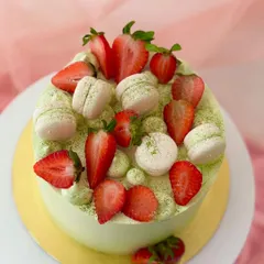 A top-down view of the matcha strawberry cake, showing the artful arrangement of sliced strawberries and macarons dusted with matcha powder.