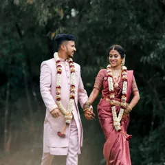A lovely shot of a bride and groom walking together, hand in hand, after their ceremony. Their coordinated pink outfits and joyful expressions make this a perfect wedding portrait.