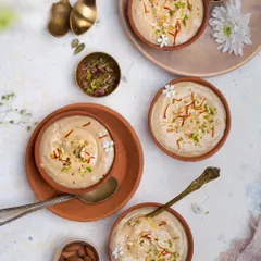 A beautiful top-down shot of payasam for Janmashtami, garnished with saffron and pistachios, styled in earthy terracotta bowls.