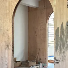The journey from a raw plywood frame to a finished, fabric-wrapped archway. This before-and-after view highlights the structural planning and meticulous craftsmanship required to create the soft, transitional moments that define the Moire studio.