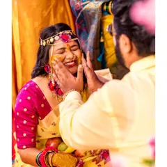 A sweet moment where the groom gently applies Haldi to the bride's face, captured up close to show her blissful expression.