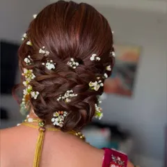 An intricate braided bun adorned with delicate baby's breath flowers. This style is both romantic and sophisticated, ideal for a wedding or engagement.