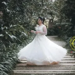 A bride-to-be twirls in a classic white ball gown in a garden setting.