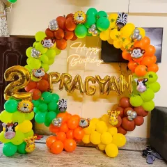 This closer shot highlights the details of the jungle balloon arrangement. You can see the mix of different colored latex balloons and the placement of the zebra, monkey, and lion foil balloons that give the decoration its playful character.