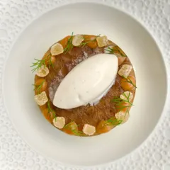 A beautifully plated dessert from our "Tasty! Tasty! Tasty!" menu. This dish features a perfect quenelle of house-made ice cream on a delicate cake, garnished with candied ginger and fresh dill.