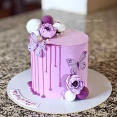 A 6-inch tall drip cake in a lovely pastel shade, created by mixing pink and purple. It's decorated with a ganache drip, delicate wafer paper butterflies, and sugar flowers.