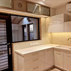 This angle highlights the sink area and the reflection in the window, showing the thoughtful lighting design. The gold-finish handles add a touch of warmth to the white cabinetry.