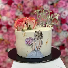 A still image of the hand-painted 'Bride to be' cake, showing the delicate artwork and the elegant combination of fresh flowers and a gold topper.