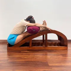 A supported forward bend using a backbend bench and bolster. This variation makes the pose accessible for those with stiff backs, providing a progressive stretch to make the spine supple.