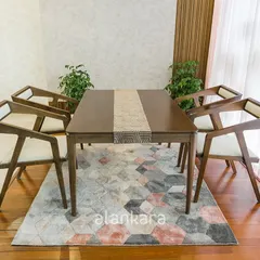 The Zircon dining set is one of my signature collections, featuring a teak wood table and uniquely designed chairs with upholstered seats. Paired with a geometric rug and set against a subtle wallpaper, this ensemble is the epitome of modern elegance.