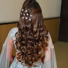 Voluminous soft curls styled into a half-updo with delicate floral accessories. This look is romantic, elegant, and perfect for an evening of dancing.