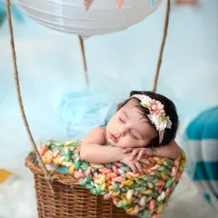 A close-up of our little dreamer in her hot air balloon basket, resting on a soft, colorful knit blanket before her big adventure.