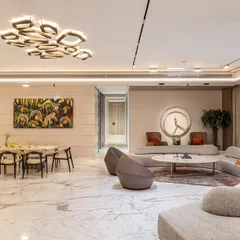 This bright and airy living room uses large marble floor tiles and expansive windows to create a sense of openness. We arranged the modular sofa and accent chairs to facilitate both large gatherings and quiet moments.