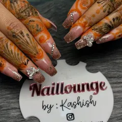 A close-up of a stunning bridal set against the client's mehendi. These long nails feature a glittery brown ombre effect, accented with sparkling 3D bow charms and rhinestones.