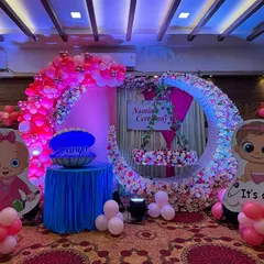 I love creating personalized themes, like this naming ceremony for baby Vanya. The setup includes a beautiful floral moon with a hanging cradle, cute "It's a Girl" cartoon cutouts, and a special seashell prop that opens to reveal the baby's name.